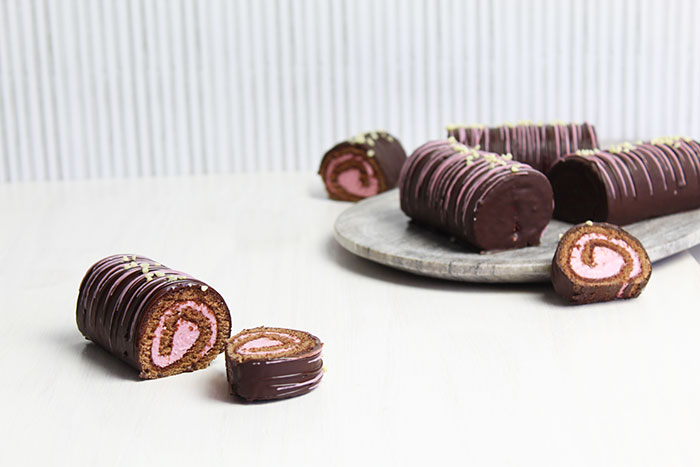 Chocolate rolled ho-hos with hibiscus filling against a white backdrop